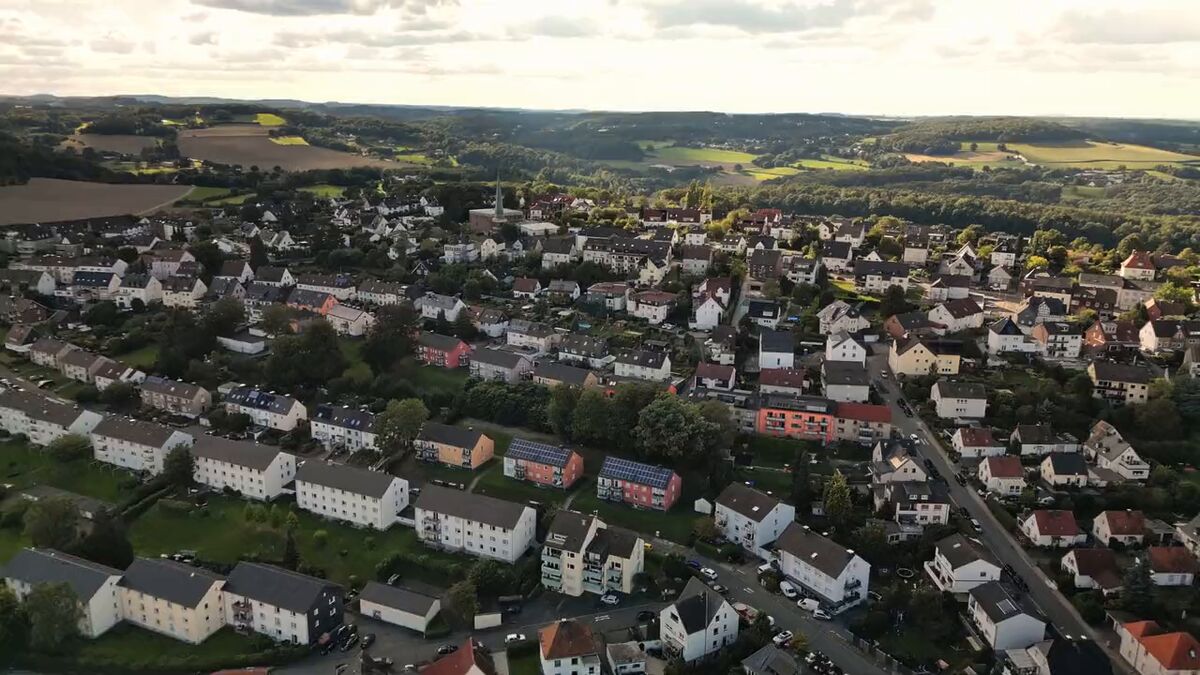 Luftaufnahme einer Kleinstadt, dahinter Felder und Hügel.
